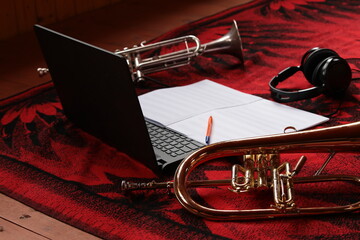 Musical theme and attributes close up. Laptop headphones notes with pen musical instruments golden...