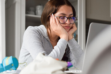 Young girl student falling asleep while studying in front of laptop computer