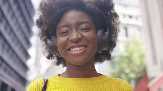 Portrait of young woman smiling as she listens through headphones, in slow motion