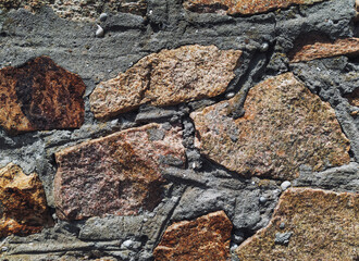 The masonry wall is made of large natural granite blocks. Stone background.