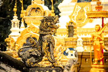 Fototapeta na wymiar A lion statue sitting guarding the door in front of the church. It is an art of northern Thailand. It is uniquely beautiful.
