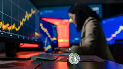 Close up shot of bitcoin cryptocurrency in front of female Asian broker trader investor type on...
