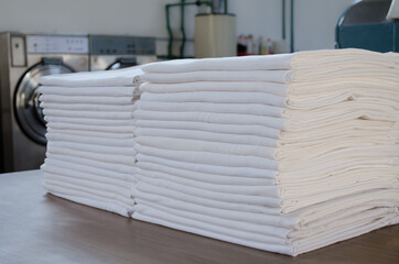 Folded clean  white sheets or fabrics in an industrial laundry.