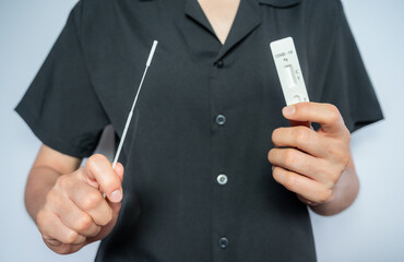 Woman holding a disposable sterile flocked swab with a test pad before doing swab by herself. Rapid antigen testing is a screening tool to help detect COVID-19.