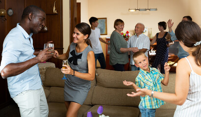 Big happy multiethnic family gathering in parental home during family party, dancing and discussing pleasant topics