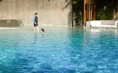 kids in swimming suit play and swim in water pool in resort