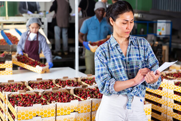 Woman controlling process of sorting of fresh ripe cherry on producing grading line