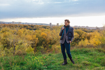 Naklejka na ściany i meble Tall handsome man walking outdoor in yellow autumn forest on the hill