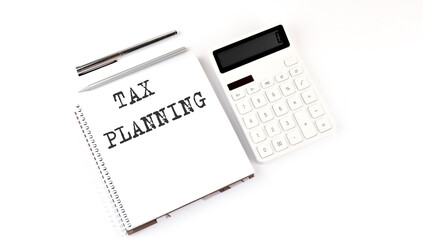 Notepad with text TAX PLANNING with calculator and pen. White background. Business concept