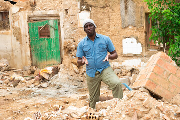 Obraz na płótnie Canvas African man behind damaged building after earthquake