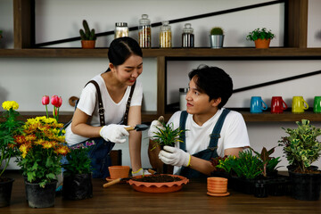 Young asian couple wearing jean overall and white t-shirt doing gardening and growing small plants...