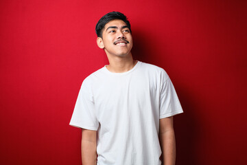 Young handsome man looking away to side with smile on face, natural expression