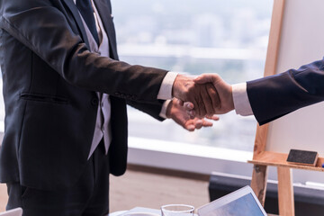 Check hand for made an agreement between businessman for business deal at skyscraper office lounge with cityscape business zone background