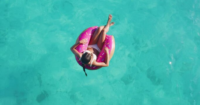 Travel beach vacation woman relaxing in pool float donut