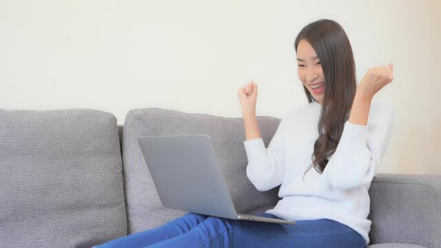 Young Asian Female Typing on Laptop, Celebrating Success With Yes Hand Gesture. Gambling Online or Cryptocurrency Concept, Full Frame Slow Motion