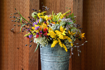 Wildflower arrangement placed in a galvanized, tall bucket. Native flowers to Western Pennsylvania. Wood background.