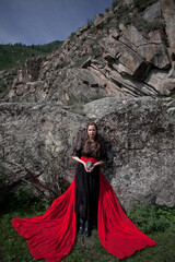 Fototapeta premium beautiful girl, brunette in a black dress with a red belt, photo session in the mountains, altai, red lips