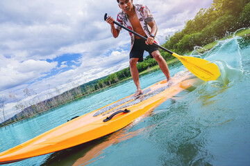 Young man have fun on stand up paddleboard. Active paddle boarder paddling at the lake. Water sport, SUP surfing tour in summer holiday vacation.