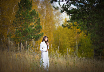 beautiful girl in a vintage dress walks in the autumn forest