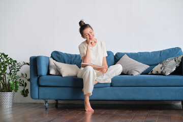 Fototapeta premium Happy woman dreaming at home. woman writes down her plans in a diary.