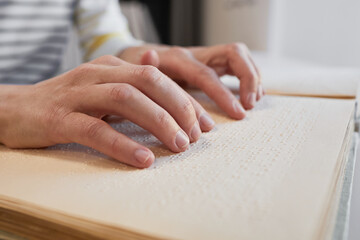 Close up of unrecognizable man reading Braille book in college library, copy space