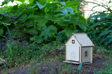 A model of a wooden house on the green grass. Close-up. Family values. Place for your text.