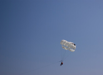 A man is flying on a parachute in the blue sky. Extreme recreation.