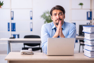 Young male employee and too much work in the office