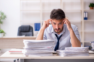 Young male employee unhappy with excessive work in the office