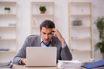 Young male employee unhappy with excessive work in the office