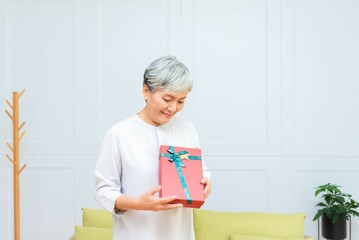 Elderly Asian woman is holding a gift with a smile