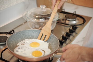 Close-up image of man frying eggs on kitchen stove