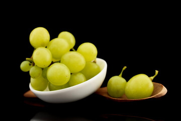 Bunch of sweet juicy grapes with ceramic white utensils, close-up, isolated on black.