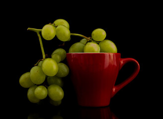 A bunch of sweet juicy grapes with a red cup, close-up, isolated on black.
