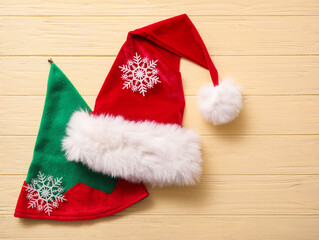 Obraz na płótnie Canvas Santa Claus and elf hats on color wooden background