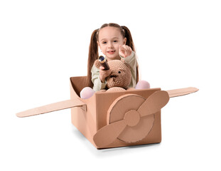 Little girl playing with toys and cardboard airplane on white background