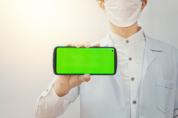 Doctor wearing medical Mask hand holding the black smartphone with green screen and camera on angle design  Horizontal positions on white-gray background