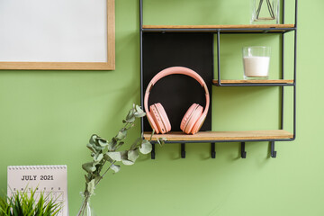 Shelf with headphones hanging on color wall