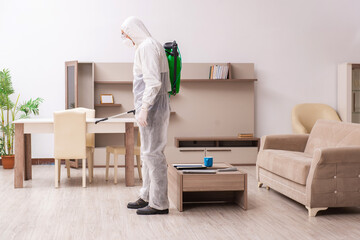 Young male contractor doing pest control at home