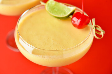 Glass of tasty banana daiquiri cocktail on color background, closeup