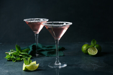 Glasses of tasty cosmopolitan cocktail, mint and limes on dark background