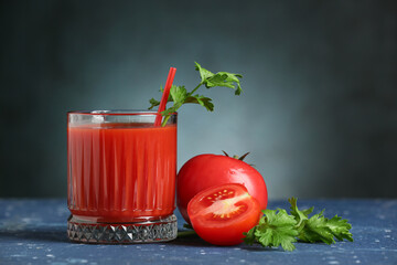 Glass of tasty tomato juice on dark background