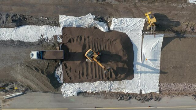 Unloading gravel at a road construction in Finland. Drone aerial top-down view of heavy equipment work.