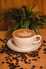 cup of coffee on a table with coffee bean and natural plant in the background
