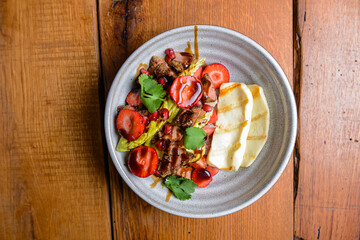 Salad with strawberries and meat, Georgian cuisine concept. Served in a plate over rustic wooden background.