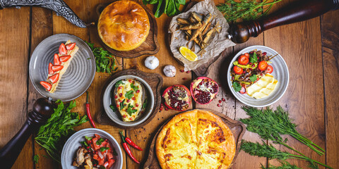 A lot of food on the wooden table. Georgian cuisine. Top view. Flat lay. Khinkali and Georgian dishes