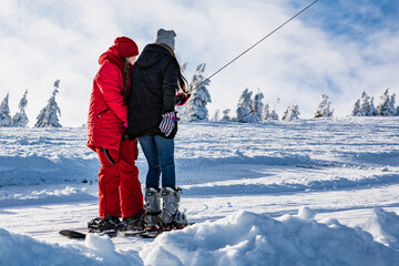two women snowboarder and skier pulling up by hill on yoke