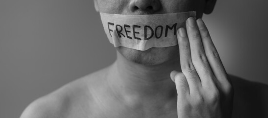 Man show three fingers  with mouth sealed in adhesive tape with Freedom message. Free of speech,...
