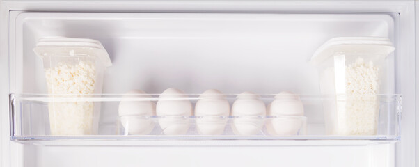 chicken eggs and cottage cheese on a shelf in the refrigerator door, side view, close-up