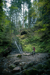 Obraz premium young hiking woman looking at waterfall